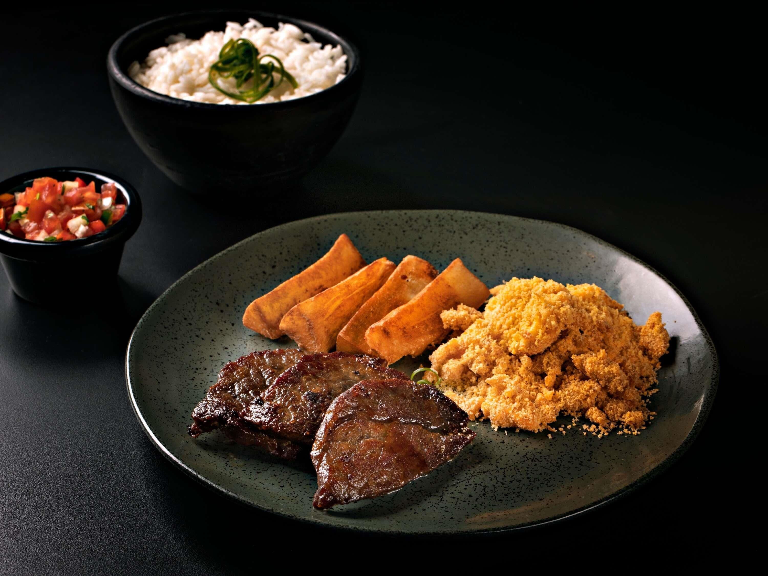 A plate with steak, fried items, and a side of rice and vegetables.