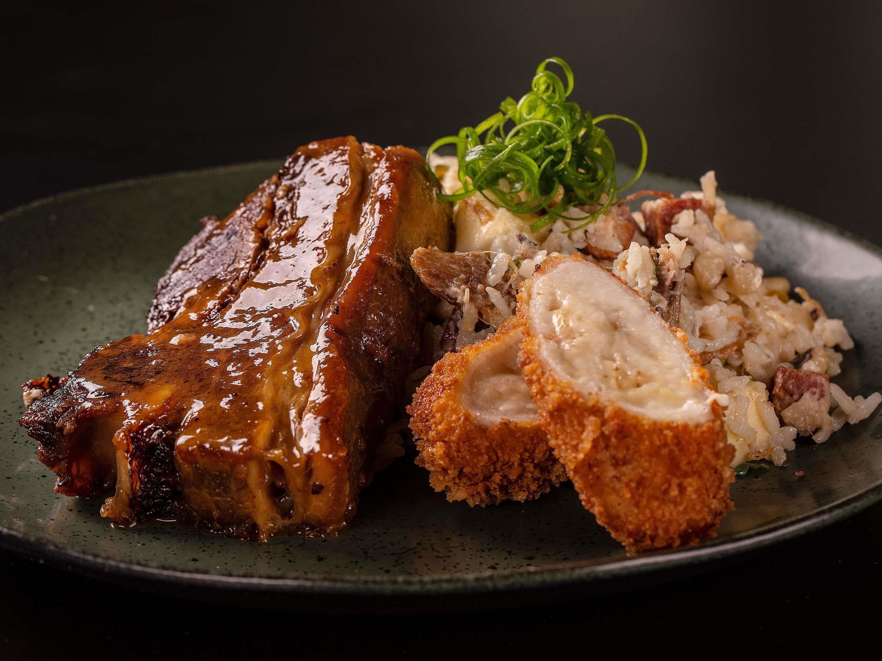 A plate with glazed pork ribs, fried chicken, and a side of rice.