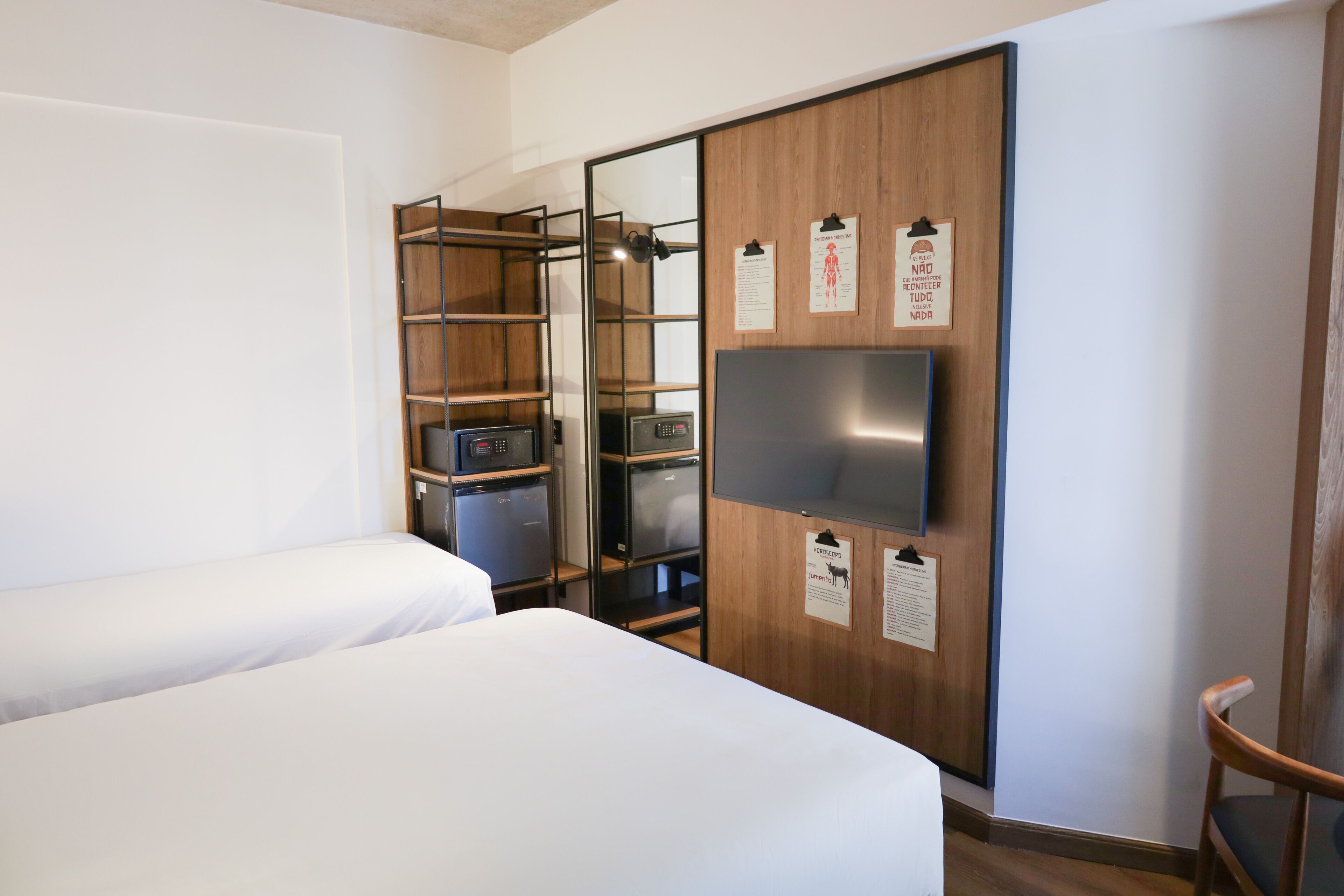 Una habitación de hotel con una cama, un armario con espejo, un televisor y una silla.