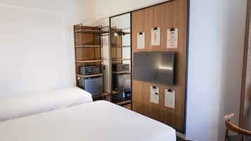 Una habitación de hotel con una cama, un armario con espejo, un televisor y una silla.