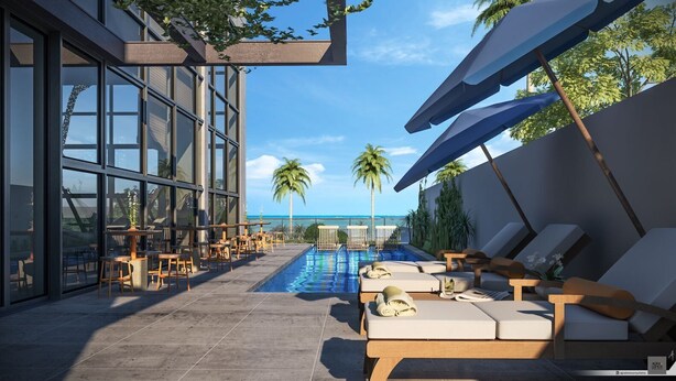 Un área de piscina en la azotea con sillones de descanso y mesas, vistas despejadas al océano, y un edificio moderno con ventanas amplias.