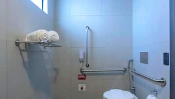 A modern bathroom with a toilet, handrails, a towel rack, and an emergency button.
