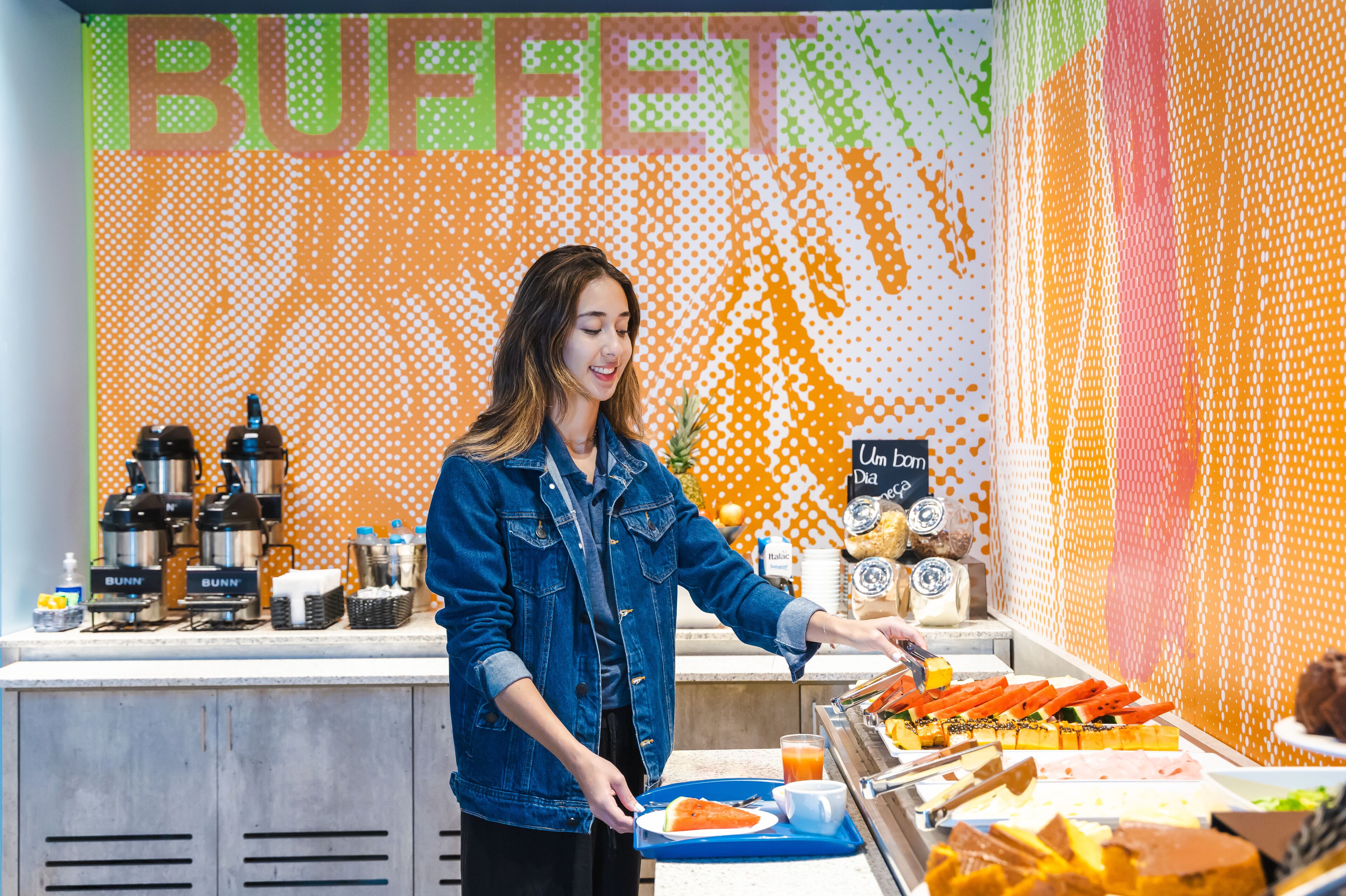 A buffet counter with various food items and beverages, a sign that reads "BUFFET", and a coffee station with branded coffee makers.