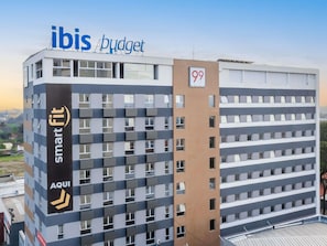 En moderne bygning med skilt for 'ibis budget' og '99 kontorer' på siden.