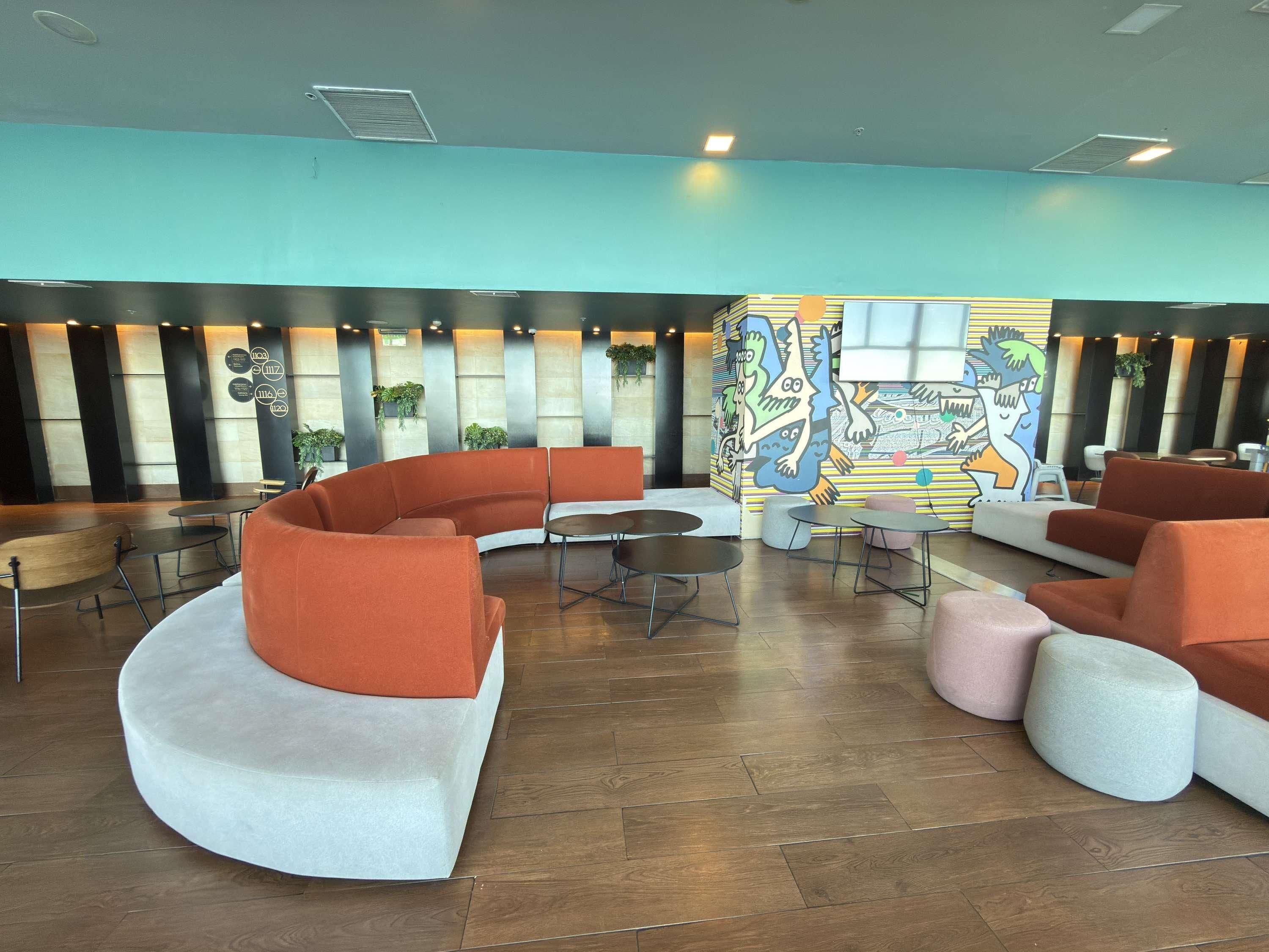 Un área de estar moderna con asientos curvos, una mesa de centro y un mural de colores en la pared de fondo.