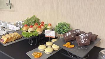 A buffet table with various food items including sandwiches, macarons, and desserts.
