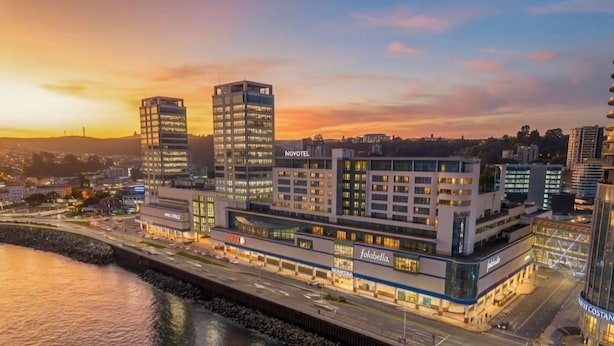 Un hotel moderno con varios pisos, vista al mar y un llamativo letrero de Novotel.