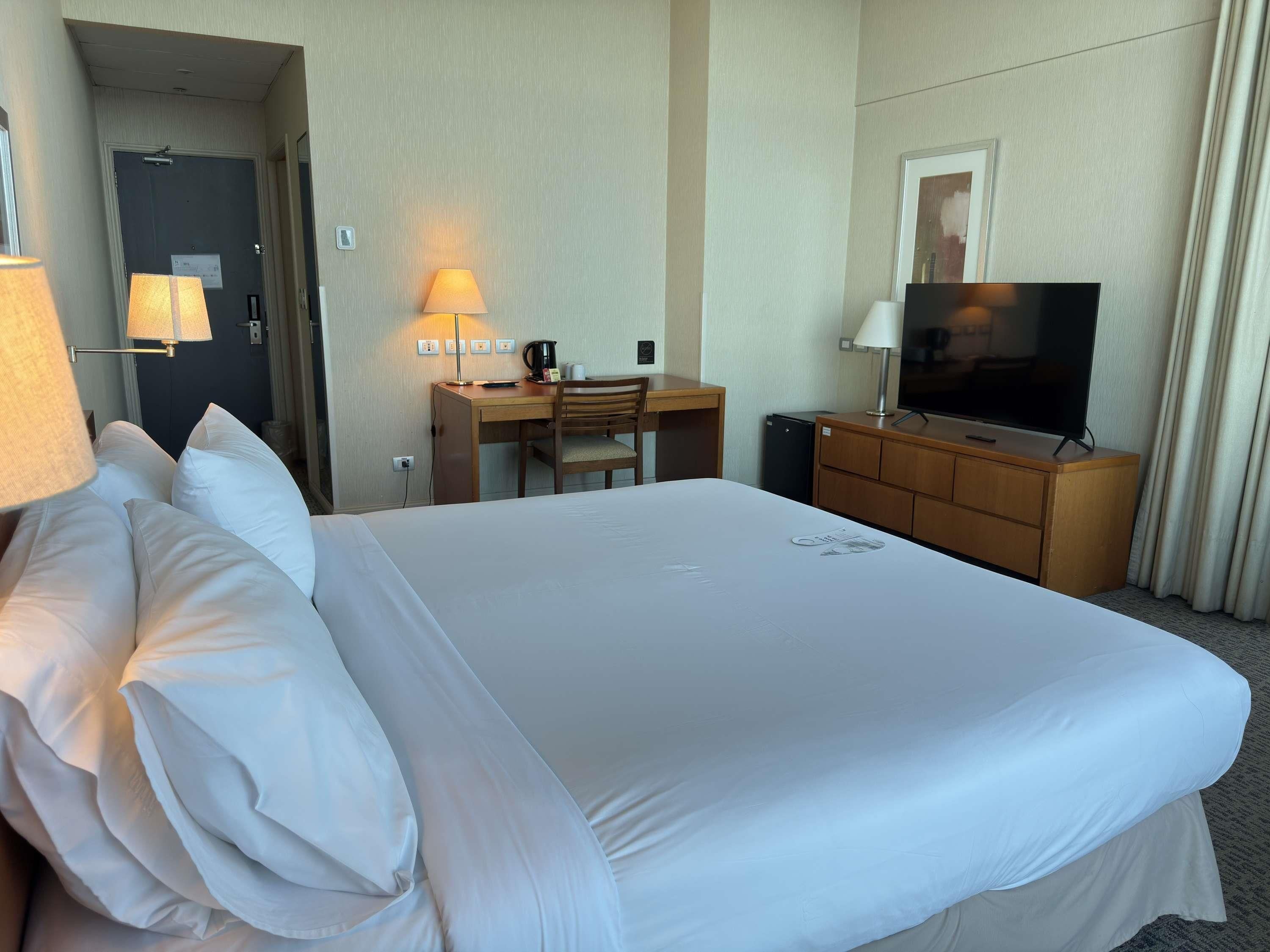 A hotel room with a large bed, a desk with a chair, a television, and a coffee maker.
