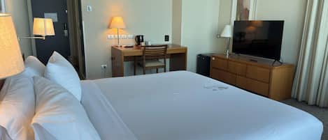 A hotel room with a large bed, a desk with a chair, a television, and a coffee maker.