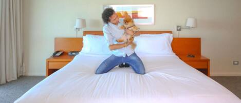 Una habitación de hotel con una cama grande, una mesita de noche con una lámpara y un cuadro en la pared.