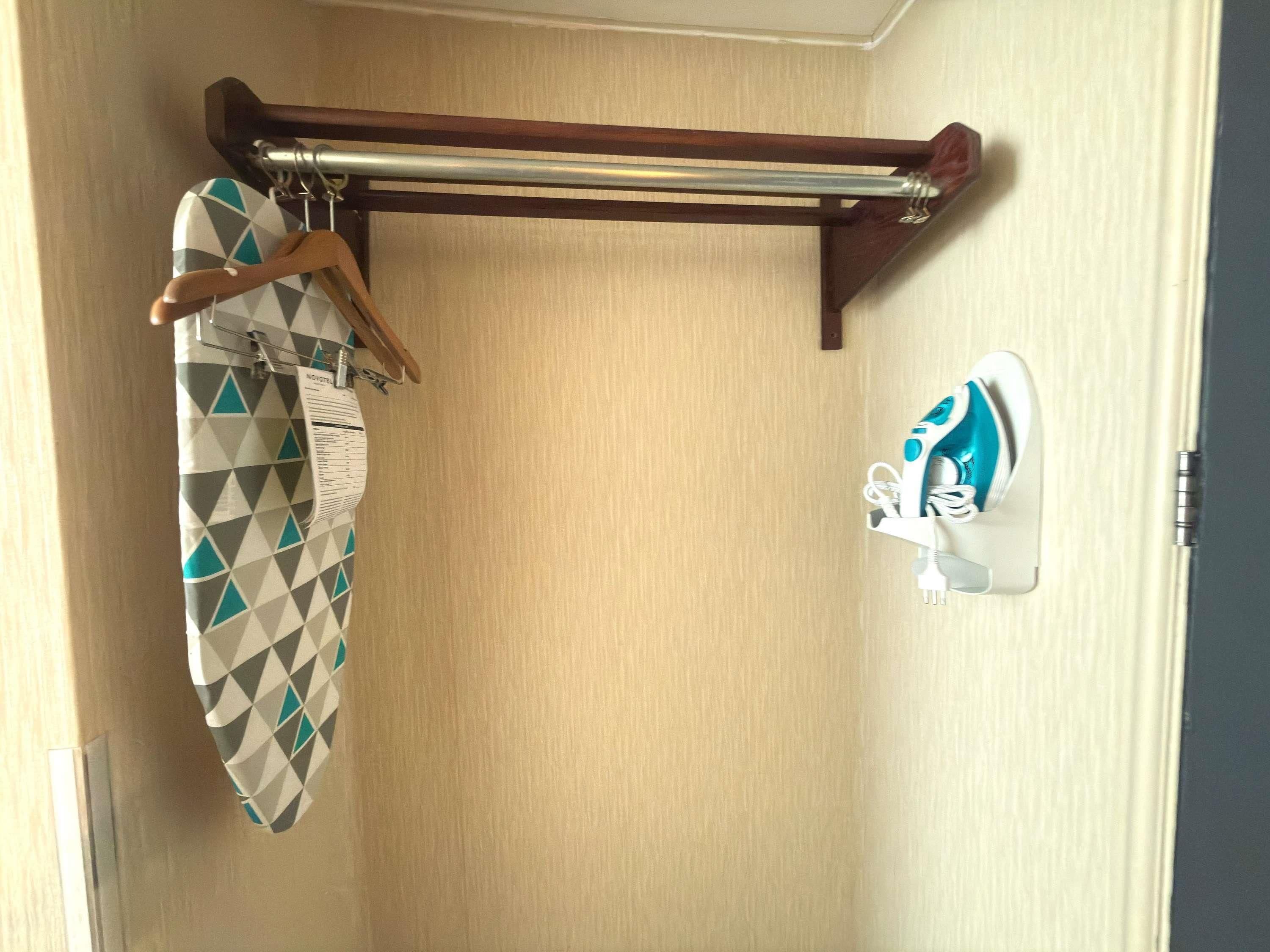 Un baño con un perchero de madera que sostiene una toalla y un albornoz con estampado geométrico.