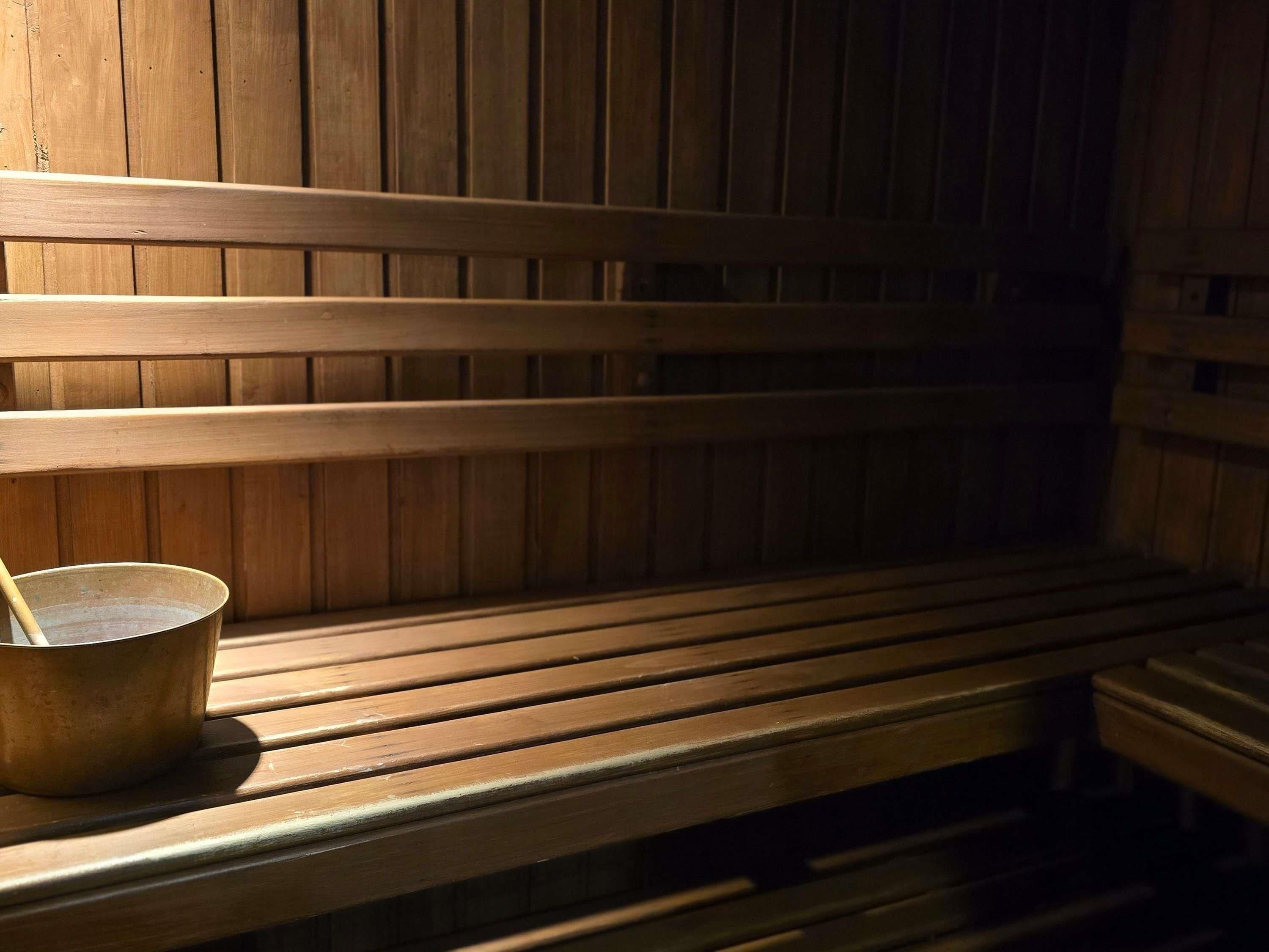 A wooden bench with a metal bucket and a wooden railing.