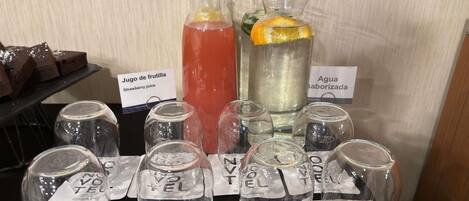 A beverage station with labeled drinks and glasses.