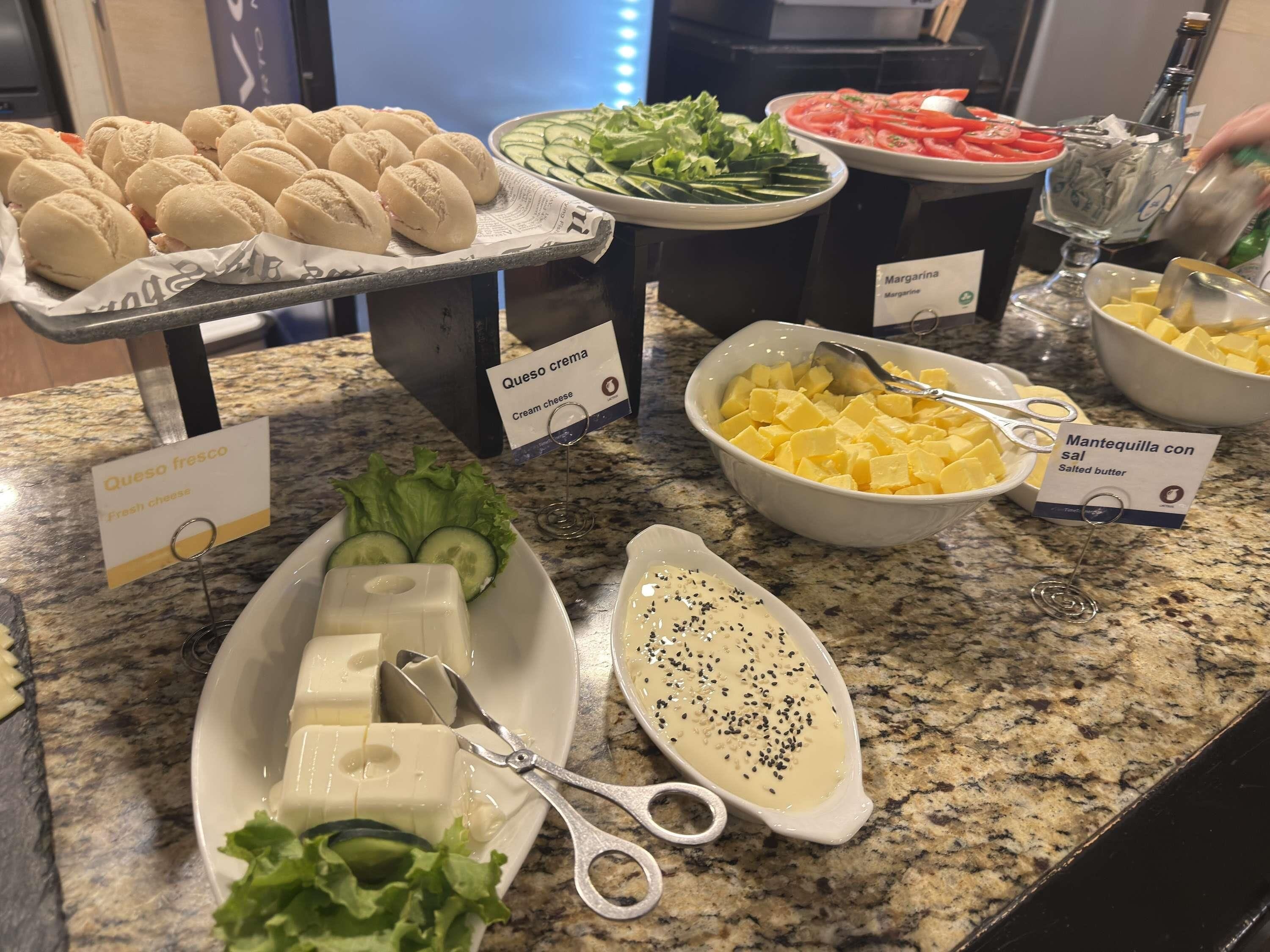 A buffet table with various food items including fresh cheese, cream cheese, and cheese cubes.