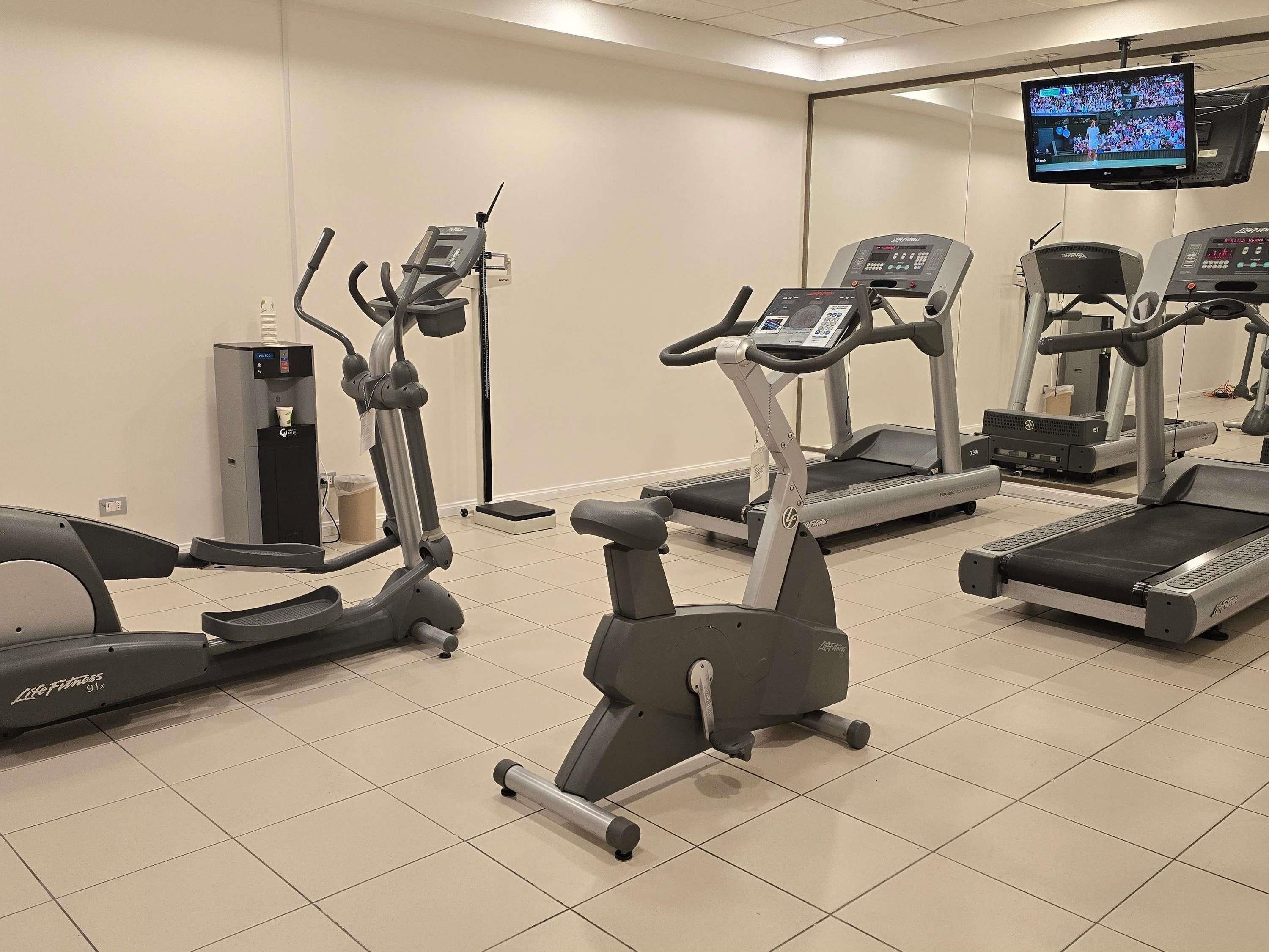 Un gimnasio con diversas máquinas de cardio, incluyendo cintas de correr y elípticas.
