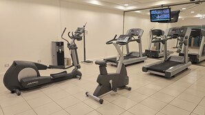 A gym with various cardio machines, a water dispenser, and a TV mounted on the wall. - Novotel Puerto Montt (Puerto Montt)