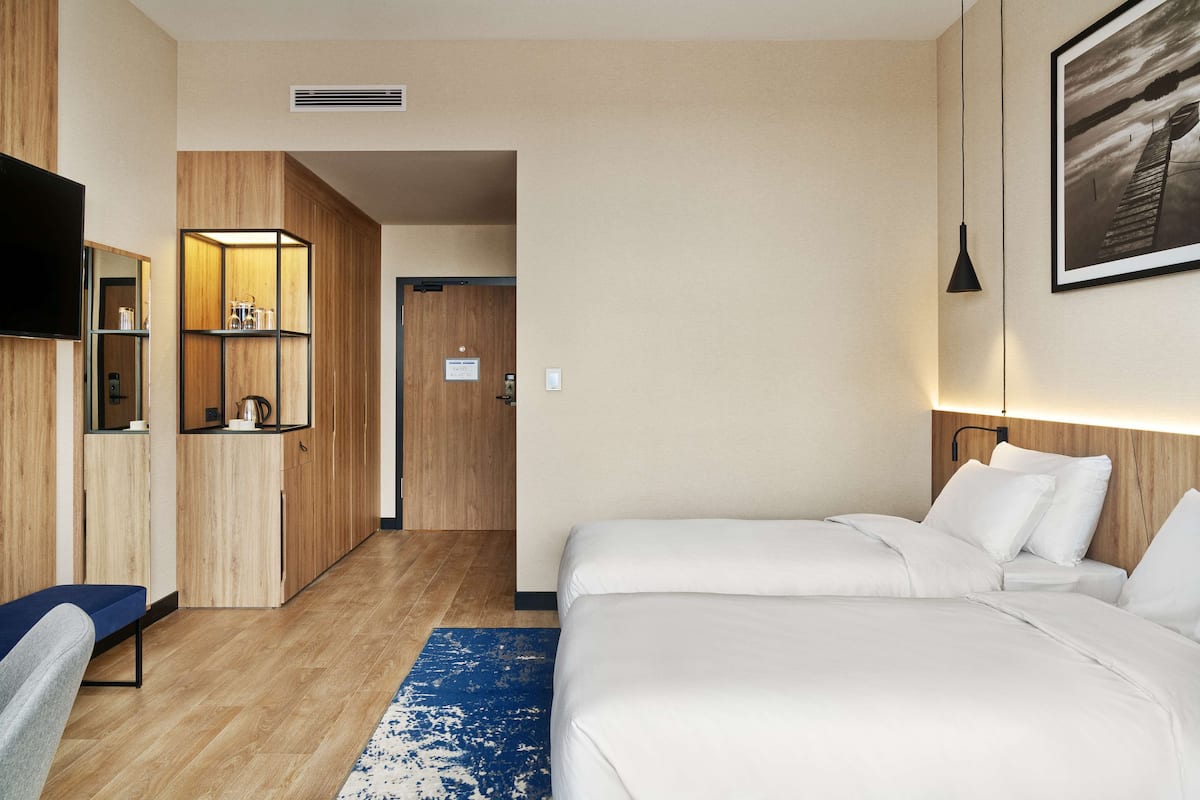 A hotel room with a large bed, a desk, a TV, and a wardrobe.