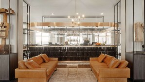 A modern living room with a sofa set, a coffee table, and a bar area in the background.