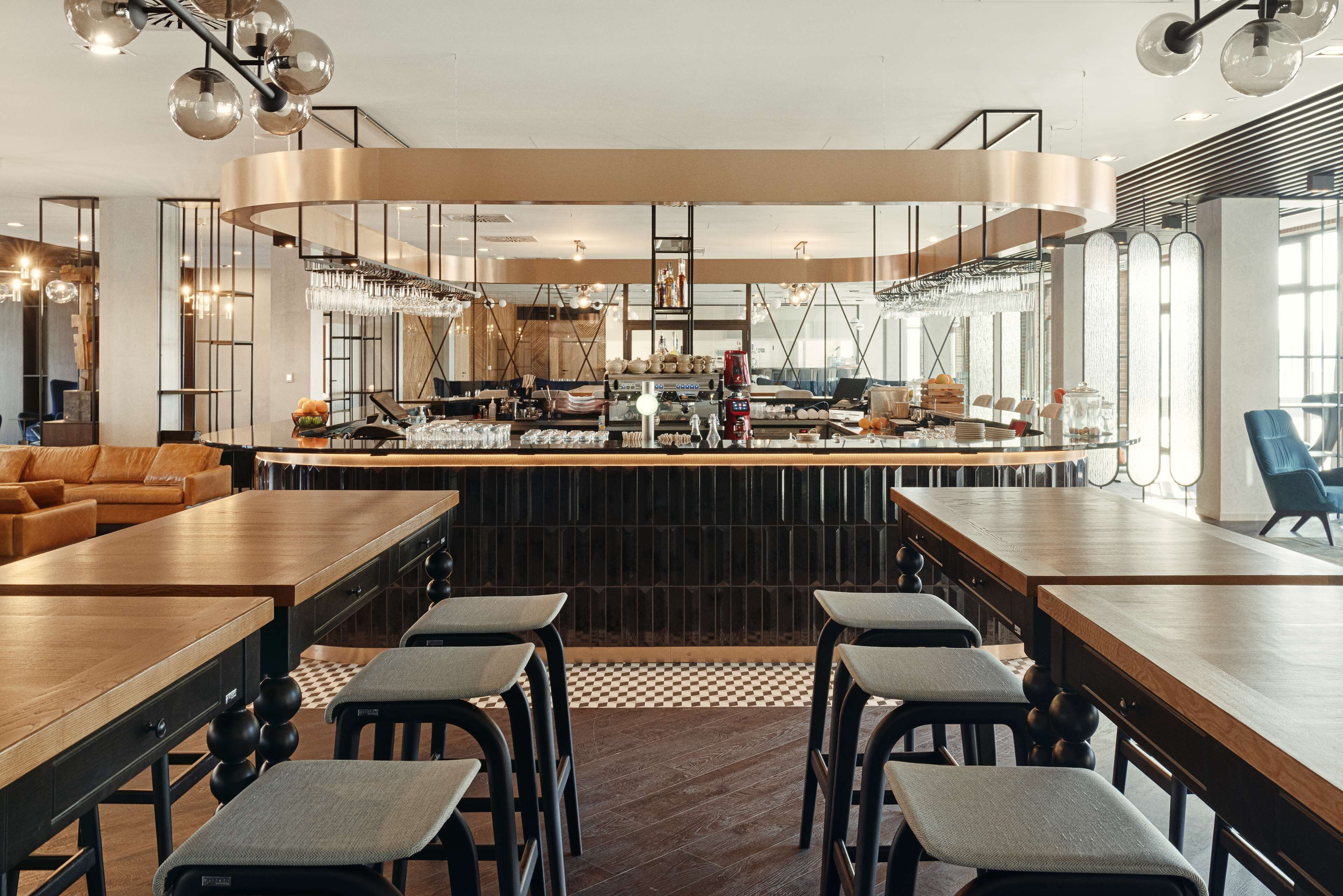 A modern restaurant with a long counter, bar stools, and a central bar area with a wine rack and glasses.