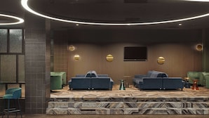 A modern lounge area with sofas, a patterned carpet, and ambient lighting.