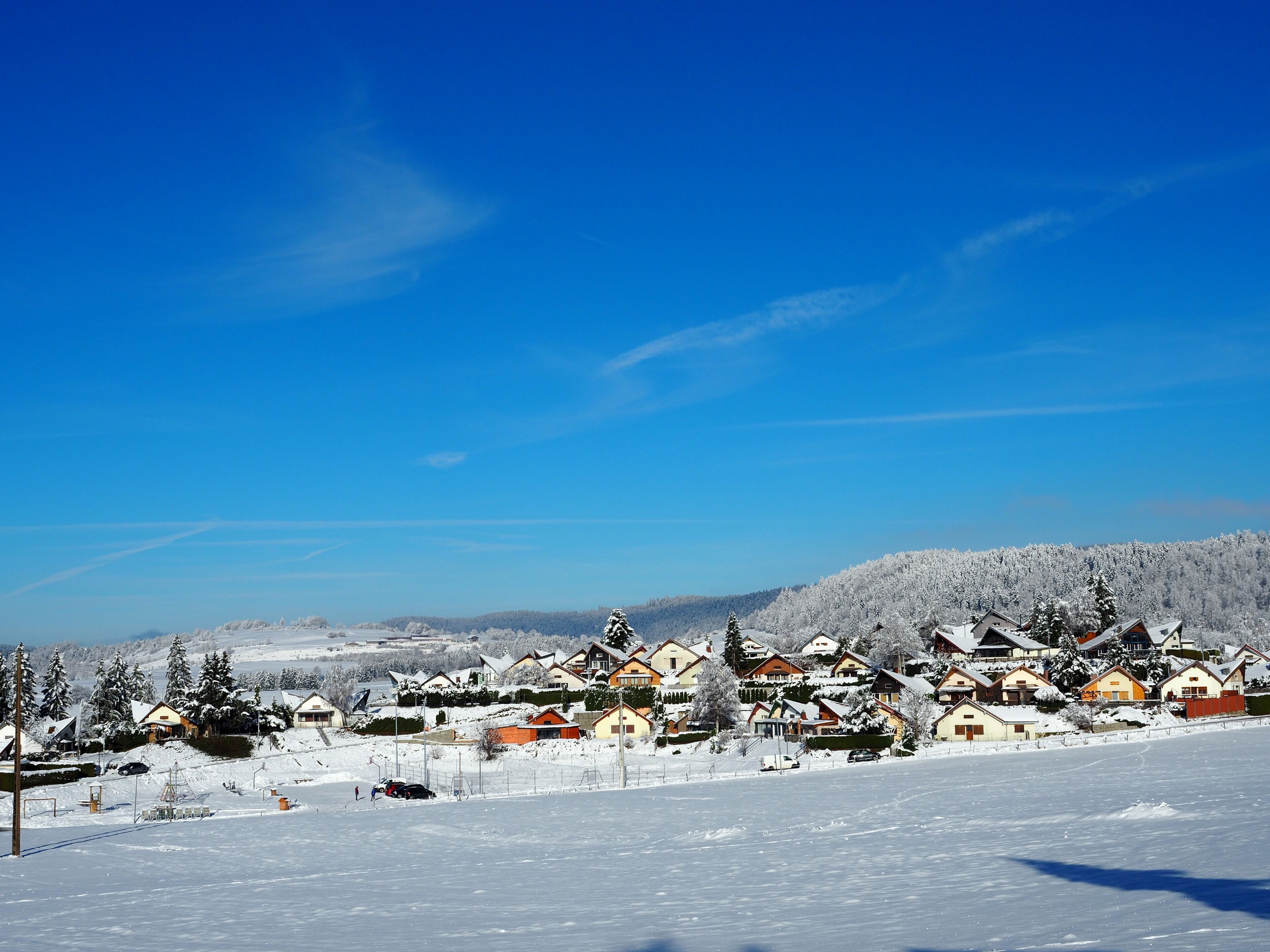 A snow-covered village with houses and a ski slope.