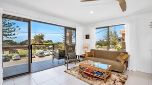 Relax in this airy living room with a sofa set, glass coffee table, and shaggy rug.