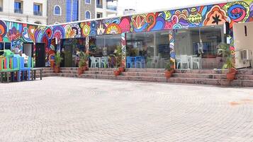 A colorful building with a vibrant mural on the exterior, outdoor seating area with chairs and tables, and potted plants.