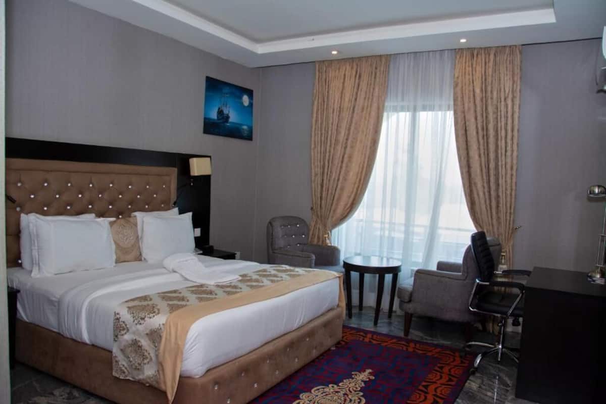 Una habitación de hotel con una cama grande, un escritorio, una silla y una mesita.