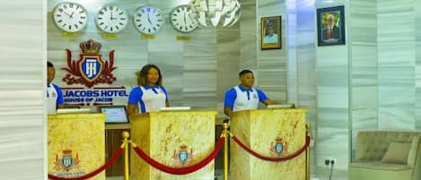 A reception area with a marble counter, clocks, and a coat of arms emblem.