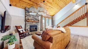A living room with a stone fireplace, wooden ceiling, and a staircase. - Central Location, Pet-Friendly, Gas Grill & Washer/Dryer. Pool On-site (Mammoth Lakes)
