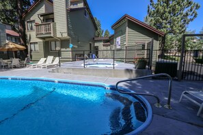 A swimming pool with lounge chairs and a hot tub area, surrounded by a fenced patio. - Central Location, Pet-Friendly, Gas Grill & Washer/Dryer. Pool On-site (Mammoth Lakes)