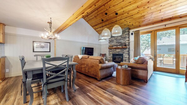 A spacious living area with a stone fireplace, wooden ceiling, and a dining area with a table and chairs. - Central Location, Pet-Friendly, Gas Grill & Washer/Dryer. Pool On-site (Mammoth Lakes)