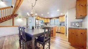 A modern kitchen with wooden cabinets, a dining table with chairs, a chandelier, and a staircase. - Central Location, Pet-Friendly, Gas Grill & Washer/Dryer. Pool On-site (Mammoth Lakes)