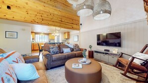 A modern living room with a sofa, ottoman, and a television. - Central Location, Pet-Friendly, Gas Grill & Washer/Dryer. Pool On-site (Mammoth Lakes)