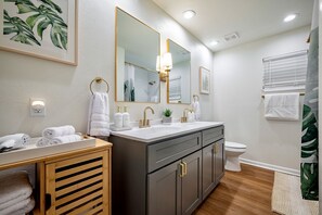 A modern bathroom with a double sink vanity, a toilet, and a shower area.