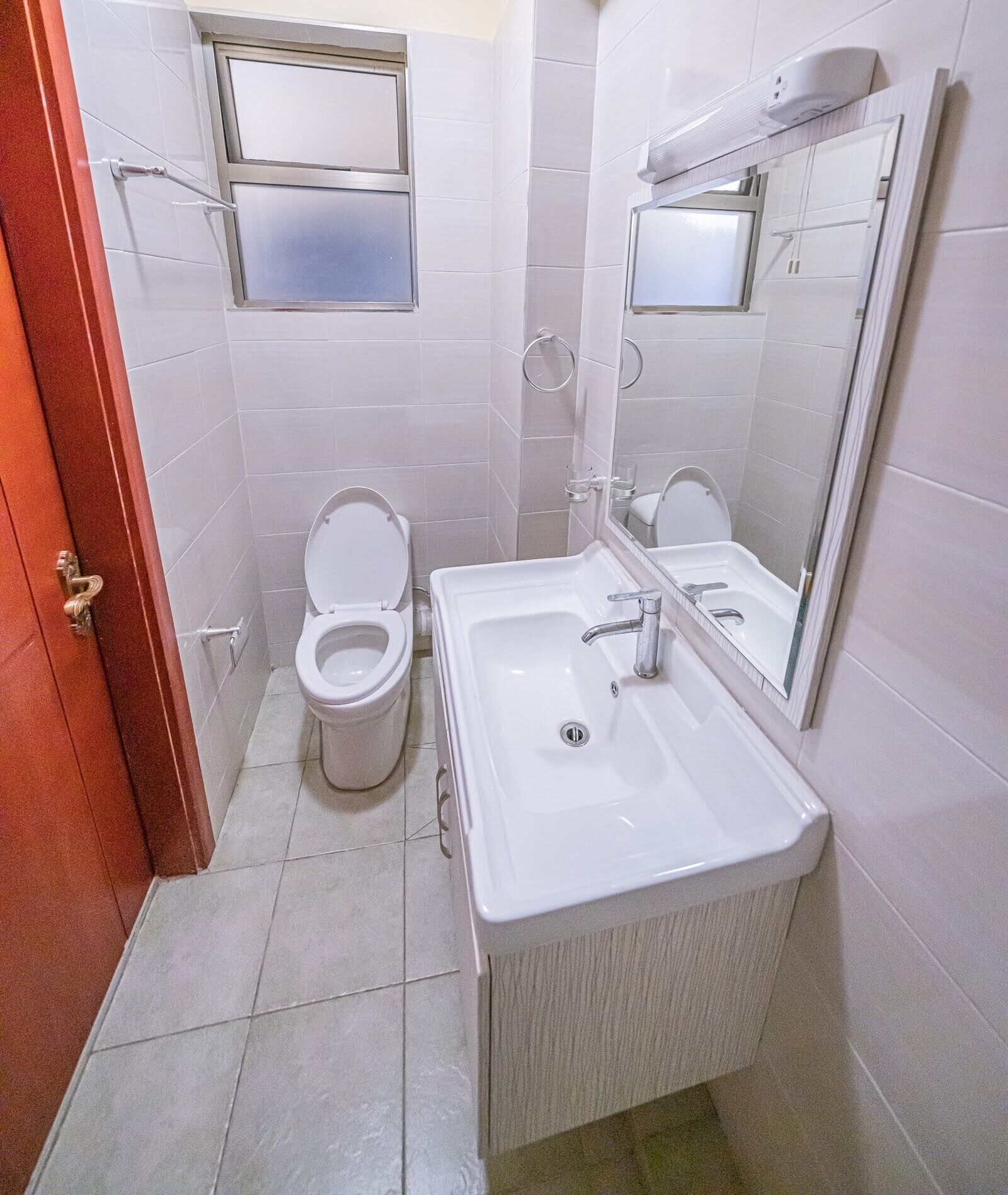 A bathroom with a toilet, sink, and mirror.