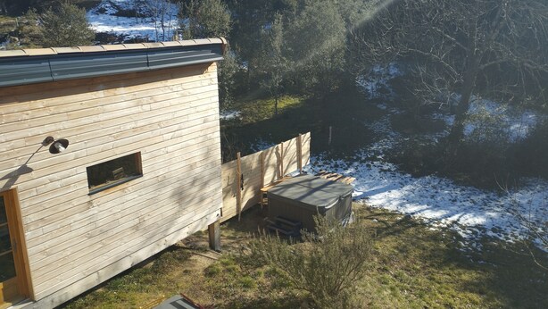 Una baita di legno con una piccola veranda e una finestra che si affaccia su un paesaggio innevato.