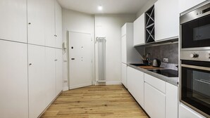Eine moderne Küche mit weißen Schränken, Holzboden und Edelstahlgeräten.