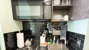 Cocina compacta con microondas, estufa, fregadero y lavavajillas.