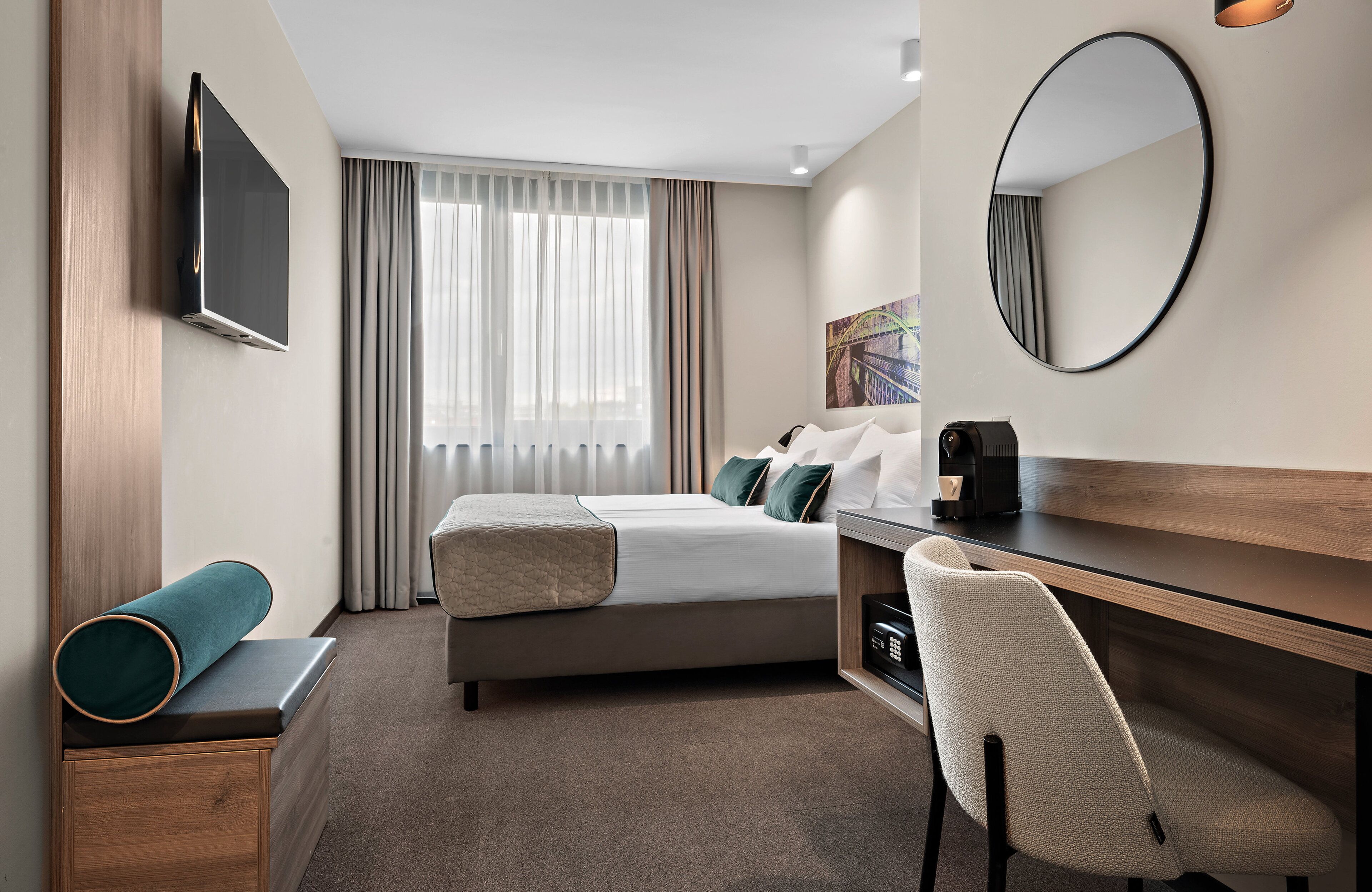 A hotel room with a bed, a desk, a chair, a television, and a large mirror.
