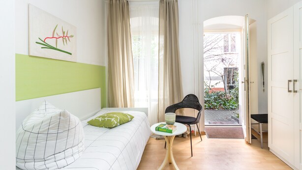 Una habitación de hotel moderna con una cama, una mesita, una silla y vistas al exterior.