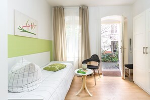 Une chambre d’hôtel moderne, équipée d’un lit, d’une petite table, d’une chaise et offrant une vue sur l’extérieur.