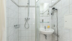 Un baño con ducha, lavamanos y espejo.
