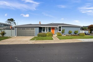 Une maison à deux étages avec un garage, un porche à l’avant et une pelouse bien entretenue.