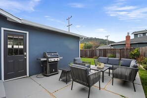 Un jardin avec un barbecue, du mobilier d’extérieur et une clôture en bois.