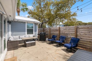 Eine Terrasse mit Gartenmöbeln, einem Grill und einem Holzzaun.