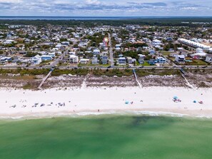 Vista aérea de un pueblo costero con playa, casas y un muelle.