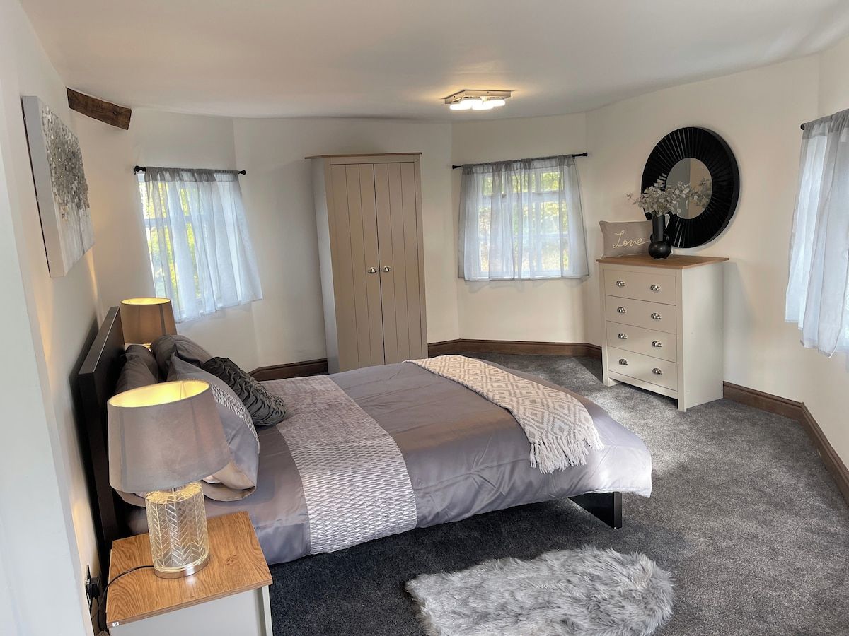 A bedroom with a bed, bedside lamp, dresser, and a mirror on the wall.