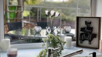 A kitchen counter with a vase of flowers, a framed picture, and a window with a view of trees.