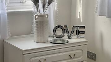 A white dresser with three drawers and a vase with feathers.